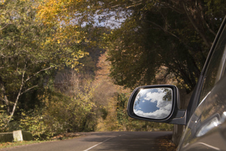 旅行理念。山路侧视图汽车镜子中美丽的天空和云朵