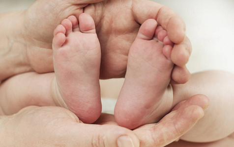父母抱着新生婴儿的双手脚。