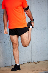 在跑步前把男人伸展的腿关起来。 健康的生活方式概念。