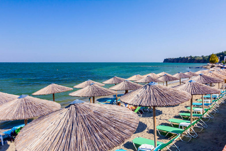 上面的遮阳伞和塑料躺椅被放置在公共海滩上，以度过一个完美的假期。