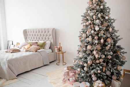 装饰圣诞树的房间里有床。 新年礼物轻圣诞节内部十二月公寓。 新年庆祝概念。