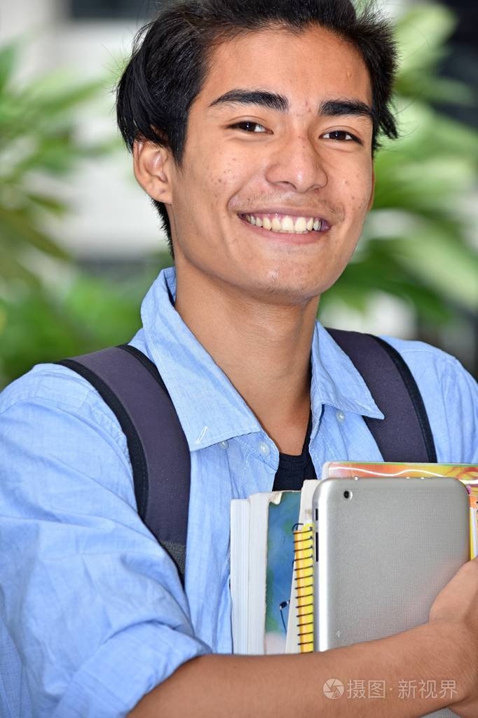 微笑的亚洲男孩学生带着书