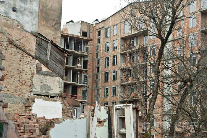 一座旧的破旧建筑在一座新建筑的背景上. 房屋的工业拆除.