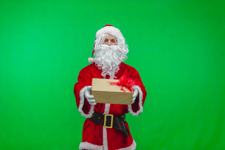 圣诞快乐。穿着红色西装的圣诞老人在绿色屏幕背景的色度键上的盒子里赠送礼物