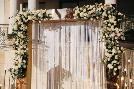 拱门在婚礼上装饰着鲜花。白色和金色。玫瑰