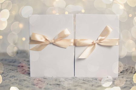 两个圣诞礼物在白色盒子与轻丝带在明亮的背景。新年假期组成横幅。为您的文本复制空间