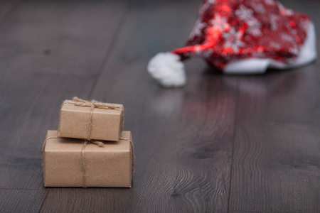 圣诞礼物或盒子来自秘密圣诞老人与圣诞老人帽子的木制背景。