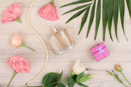 礼品盒瓶香水珠上的一串白色和粉红色的花，绿叶在木制背景上。 沃门化妆品。 上面的风景。