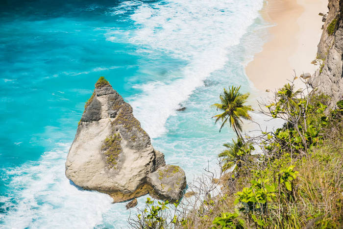 热带海滩与椰子棕榈和岩石在努沙佩尼达巴厘岛印度尼西亚。