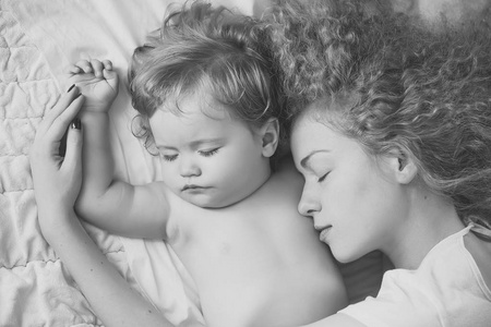 快点睡图片年轻温柔的母亲,一头浅金色的卷发,拥抱着小而可爱的男性