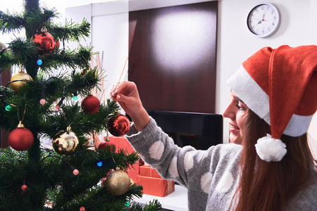 穿毛衣的女人用球装饰圣诞树的特写形象。新年和圣诞节。假日概念。