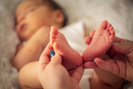 漂亮的婴儿脚在妈妈手里。小男孩的脚，新生婴儿的脚，新生婴儿的手指，