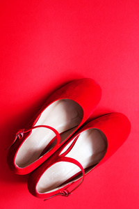 红色背景上的红色女鞋。 女性时尚概念背景。