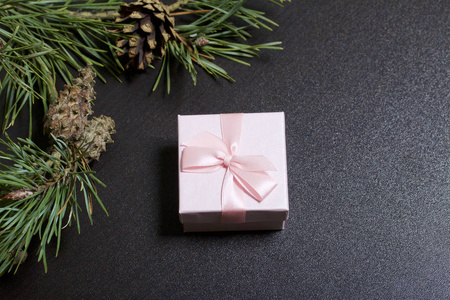 包装礼物。 礼品盒。 附近是一根带锥的松树枝。 在黑暗的背景下。