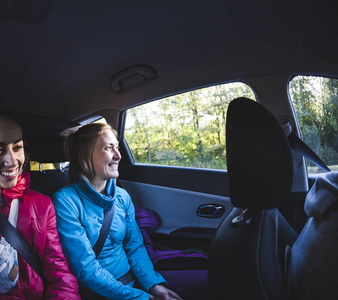 两个女人坐在汽车的后座上. 女朋友在搭便车. 乘客在长途旅行中.