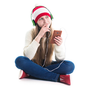圣诞节的寒假的快乐。青少年概念微笑的年轻女子在红色帽子与智能手机和耳机是听音乐和在白色背景