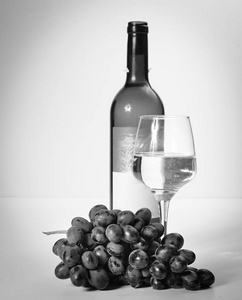 一杯白葡萄酒，一串葡萄，一个开放的瓶子。 白色背景。