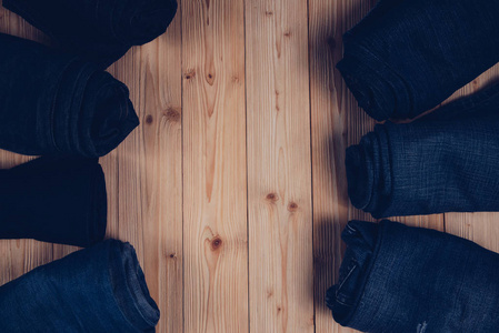 卷磨损牛仔裤或蓝色牛仔裤牛仔系列粗木桌背景与复制空间旧时尚风格的概念。