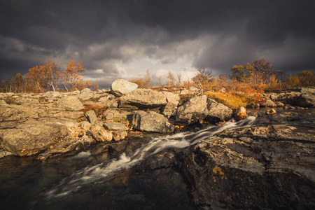 山涧上的瀑布。 挪威赛兰山的秋天。 古达伦地区。 乌云和五颜六色的叶子。