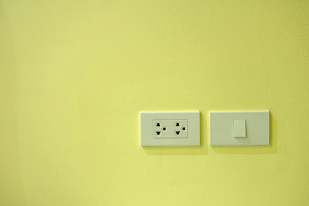 安装在黄墙上的白色电动插座