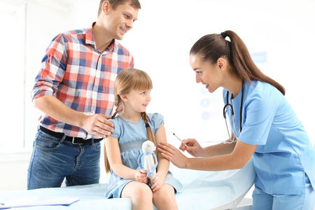 s doctor vaccinating little girl near parent in hospital