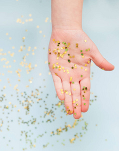 s hands with golden confetti stars on blue background.