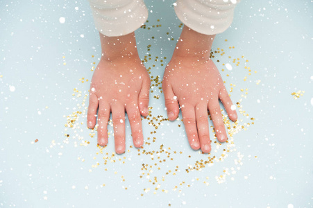 s hands with golden confetti stars on blue background.