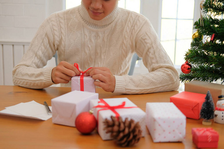 男人穿着奶油毛衣包装圣诞礼物盒。 圣诞节新年假期庆祝活动。