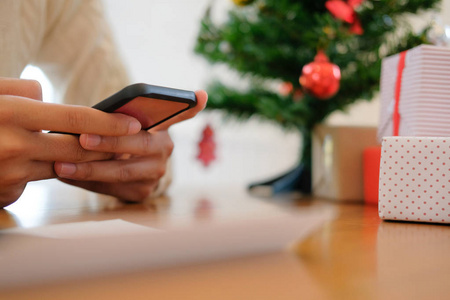 男人穿着奶油毛衣，用手机智能手机装饰圣诞。 圣诞节新年假期庆祝活动。