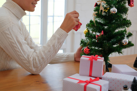 穿着奶油毛衣装饰圣诞树的人。 圣诞节新年假期庆祝活动。