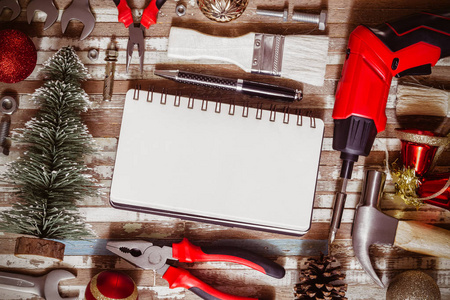 圣诞快乐和新年快乐工匠工作空间背景概念，各种方便的DIY工具与圣诞节装饰。 顶部视图与空白笔记本为您的文本。