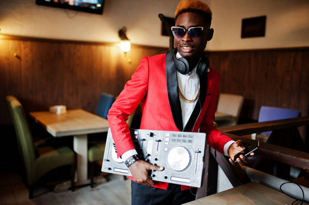 时尚非裔美国人模特DJ的红色西装与DJ控制器。