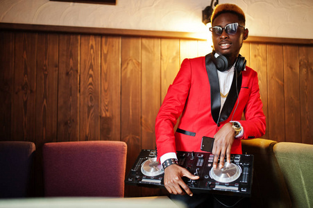 时尚非裔美国人模特DJ的红色西装与DJ控制器。