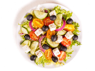 希腊沙拉与费塔奶酪，橄榄，西红柿，黄瓜，胡椒和油橄榄在白色盘子。 餐厅菜单。 免费的文本空间。 孤立于白色背景