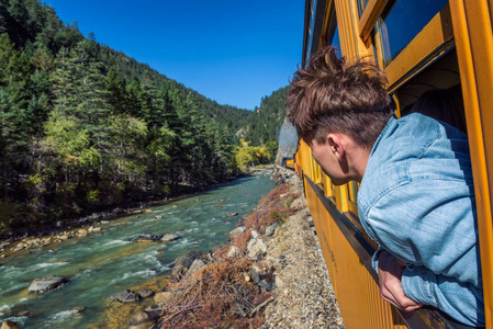 从火车车窗往外看的年轻人照片