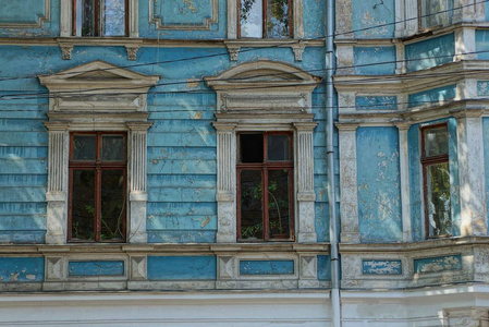 蓝色混凝土墙上的两扇旧棕色窗户