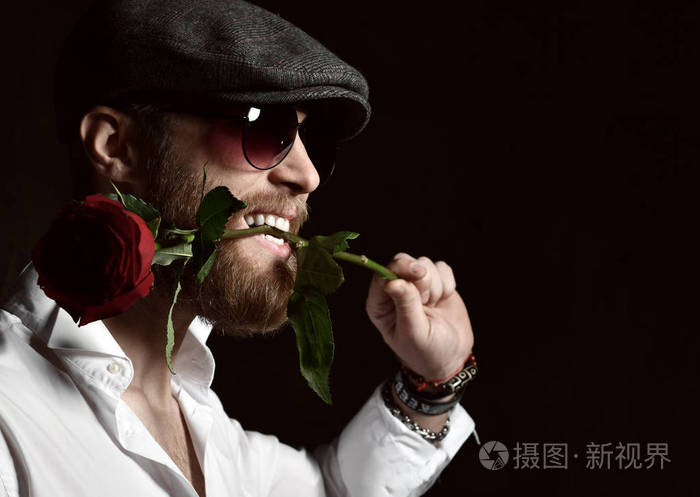 带着胡子,戴着帽子的残忍的男人嘴里拿着红玫瑰约会
