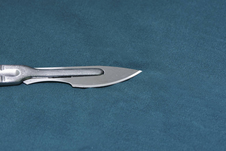 手术室绿色手术台上用锋利的刀片合上手术刀