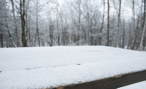 圣诞快乐，新年快乐，问候背景与桌子。冬季景观与雪和圣诞树。