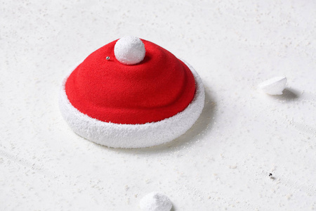 圣诞老人帽子当代草莓慕斯蛋糕在白色盘子白色背景。