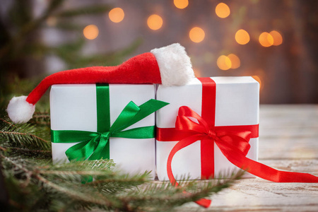 圣诞白盒或白色木桌上有圣诞老人帽子的礼物