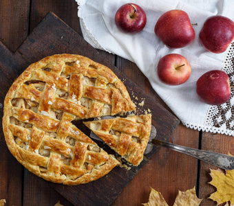 在棕色的木板上烤传统的水果蛋糕，在白色的纺织餐巾上烤新鲜的苹果