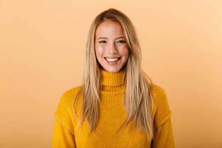 一位微笑的年轻女子的肖像，她穿着毛衣，站在黄色背景上，看着摄像机