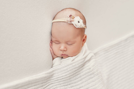 可爱的新生婴儿躺在白色的毯子里。 婴儿用品包装模板。 新生儿特写肖像，脸上带微笑。 健康和医学概念。