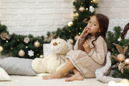 可爱的女孩喝热可可, 并发挥与泰迪熊在家里。圣诞节