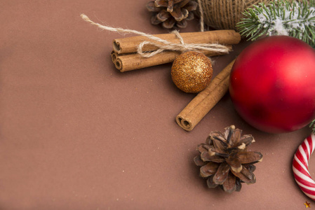 金色，红色圣诞球，肉桂棒，球果，棕色背景的糖果