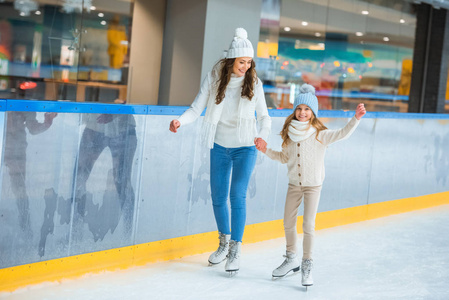 微笑的母女俩牵着手在溜冰场上滑冰