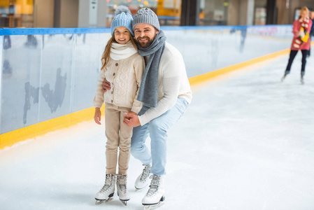 快乐的小女儿和爸爸在溜冰场