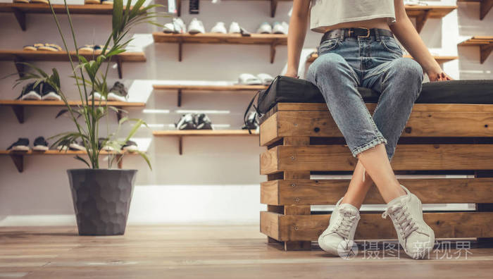 在购物中心,一个双腿交叉坐着的女人在尝试新运动鞋.