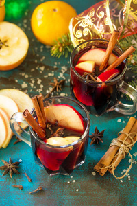 圣诞用香料覆盖葡萄酒或桑格里亚。 两杯热覆盖葡萄酒与苹果和香料在蓝色石板桌上。